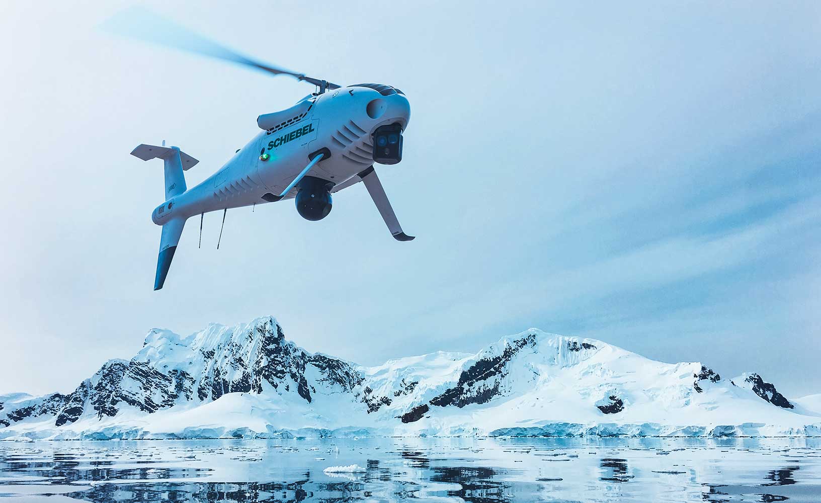 北極圏の海上を飛行する白色のSchiebel CAMCOPTER。