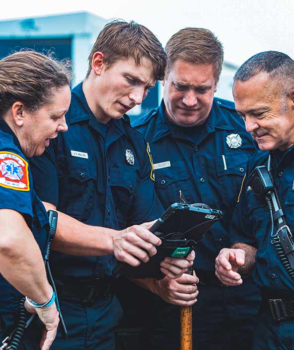 Polizei, Feuerwehr und Rettungsdienste schauen sich die Unfallinformationen und -details auf einem Tablet an.