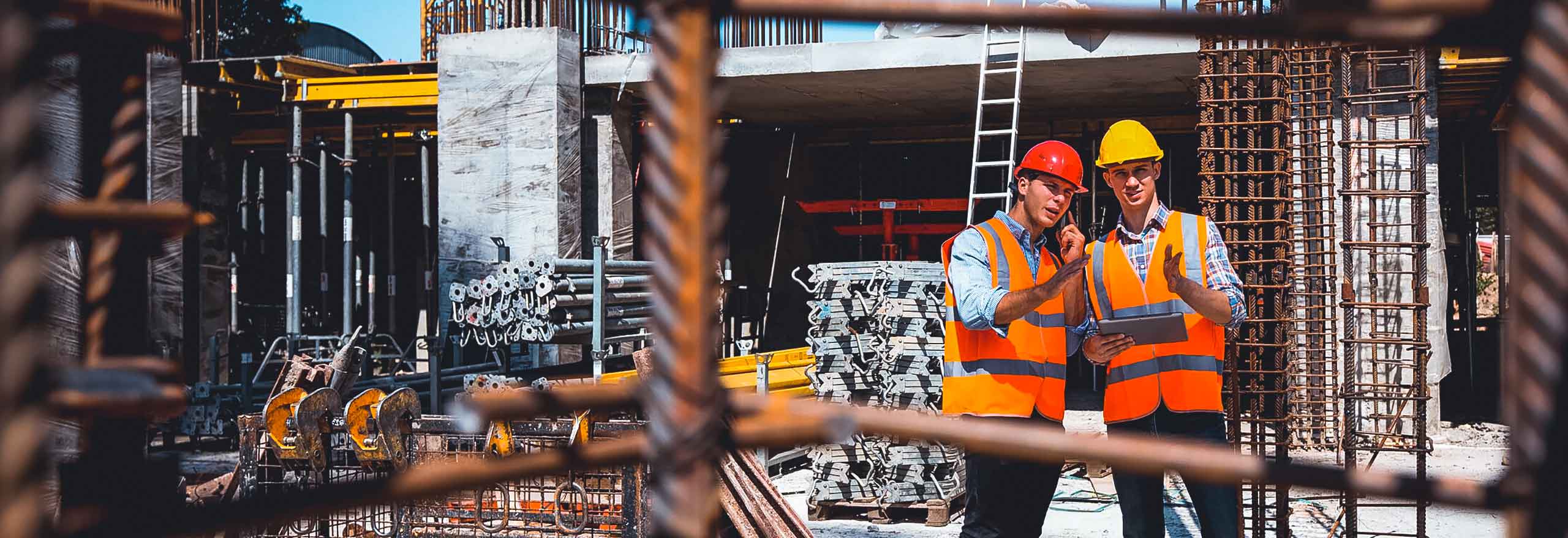 Arbeiter in Schutzhelmen und Warnwesten sprechen auf einer Baustelle