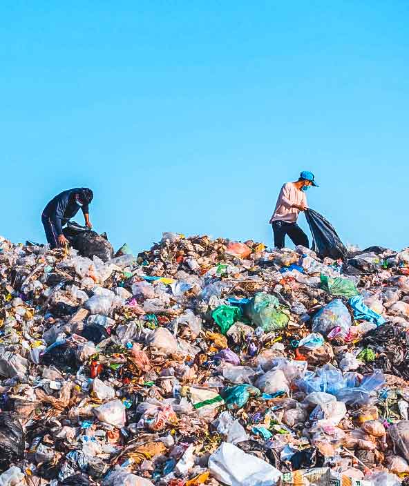 Due uomini smistano in un grande mucchio di spazzatura