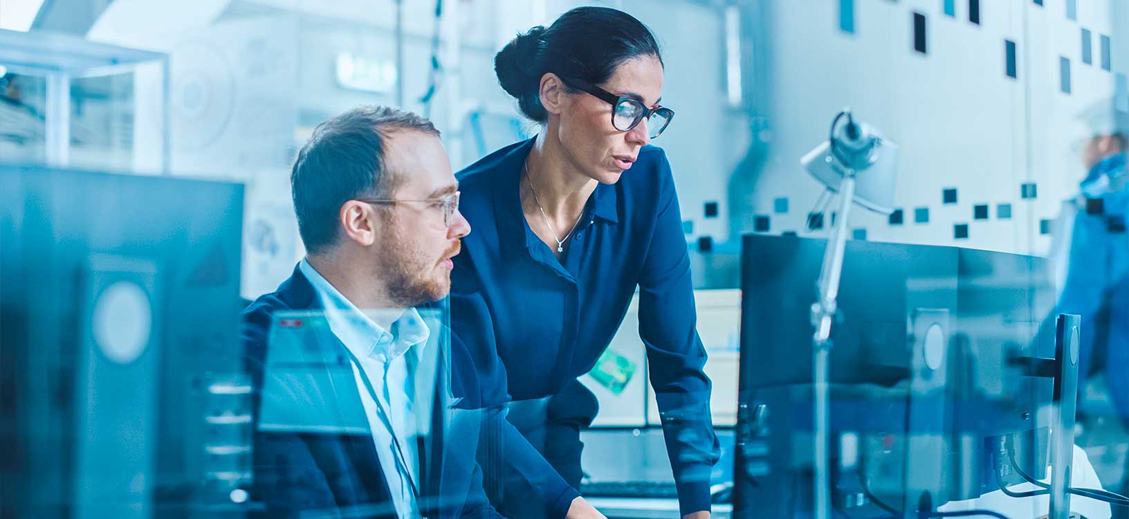 Female Supervisor Talks to a Male Electrical Engineer Working on Computer with Hexagon CAD Software