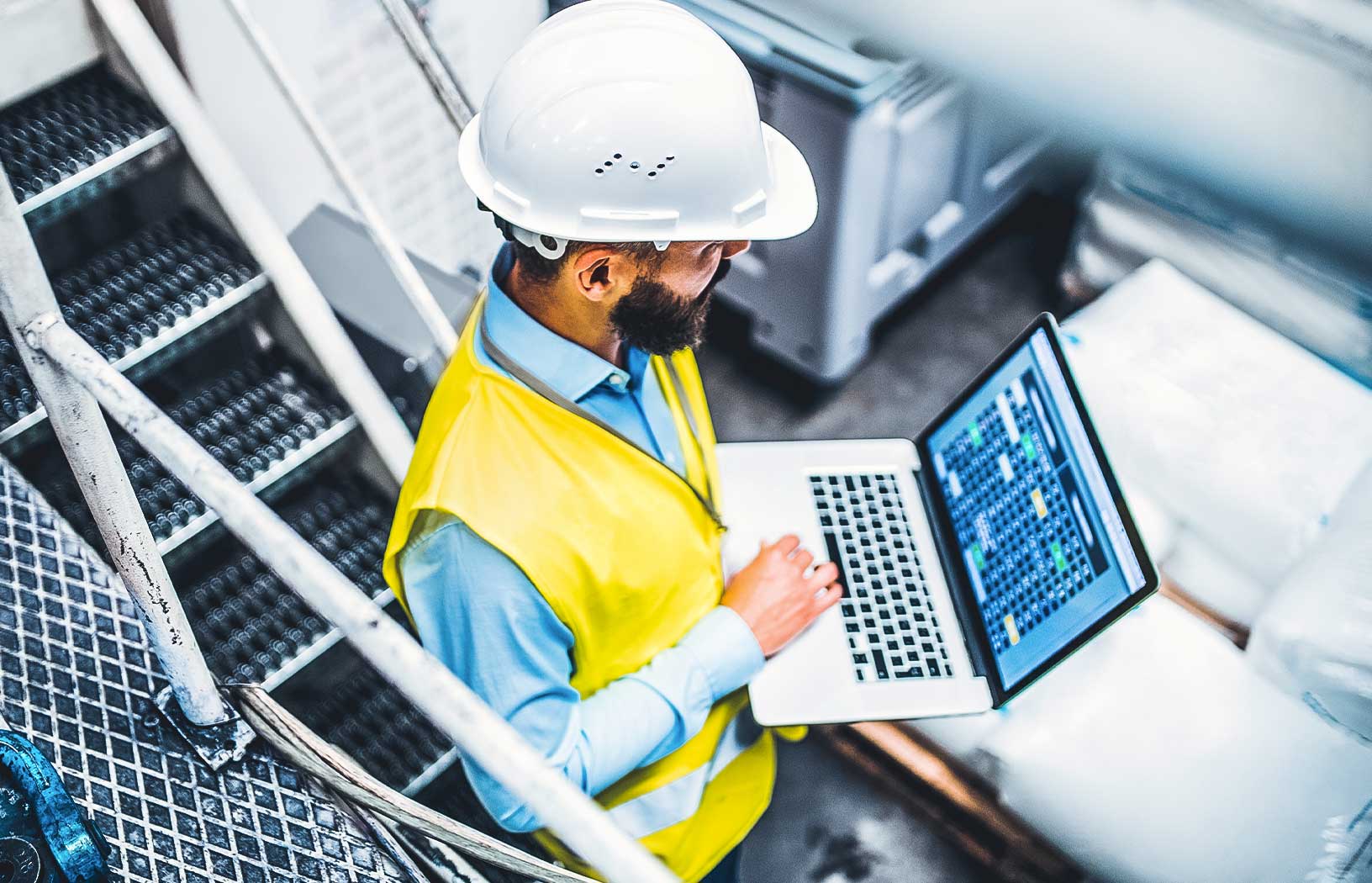 Industrial engineer with a laptop in a factory, working with data. 